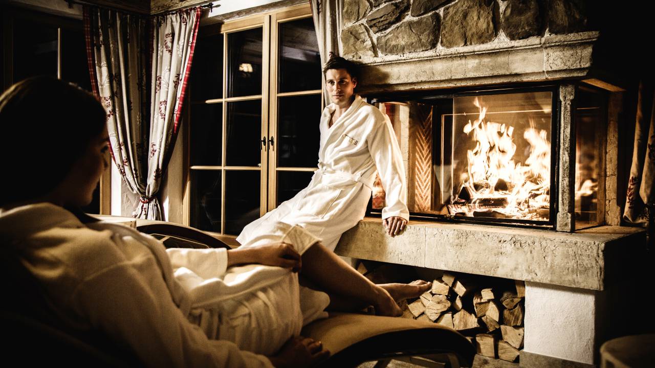 Man in a bathrobe in front of a fireplace in the spa hotel Kristall